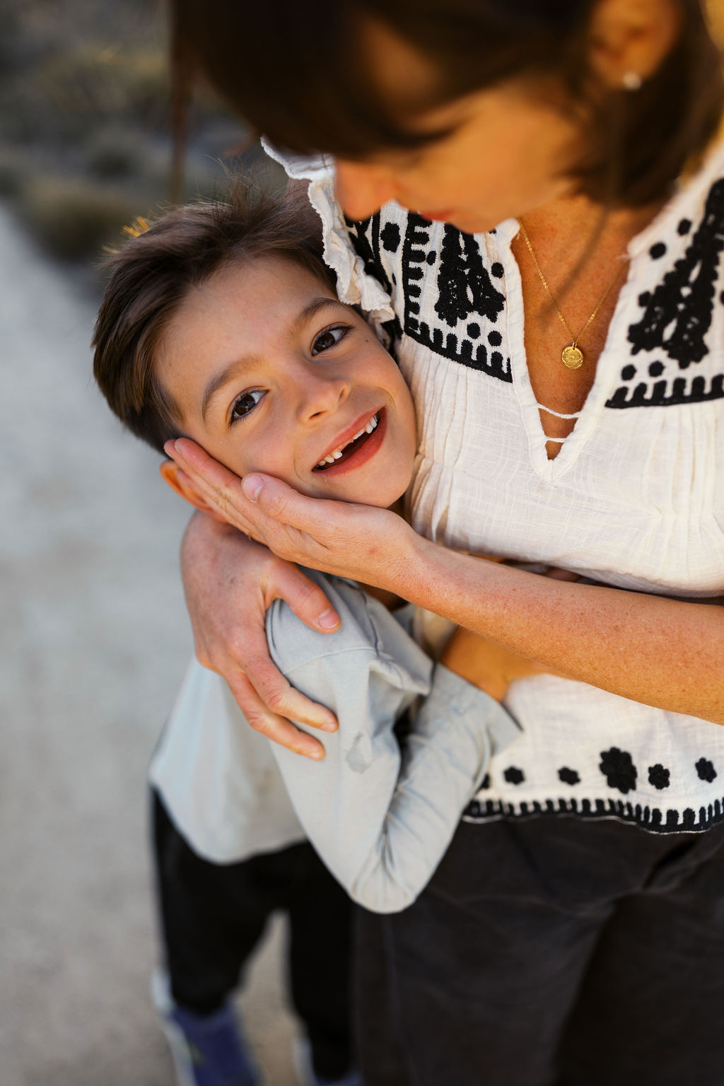 Mom holds her smiling son's face close in the evening light