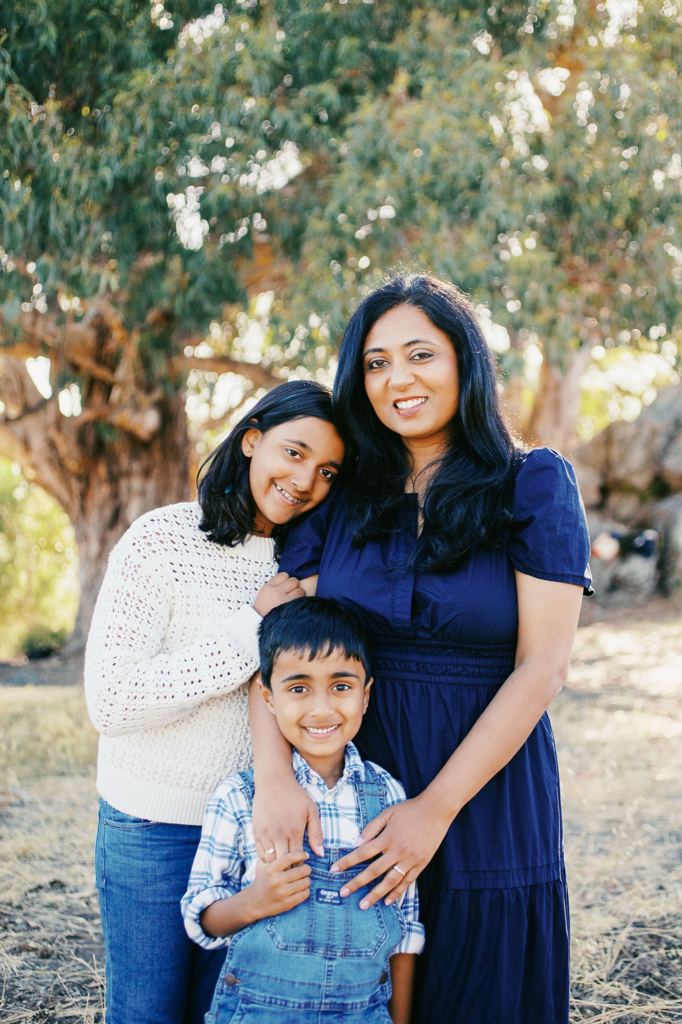 Mom with her daughter and young son beneath the Hippie Tree's canopy, soft backlight through the eucalyptus leaves