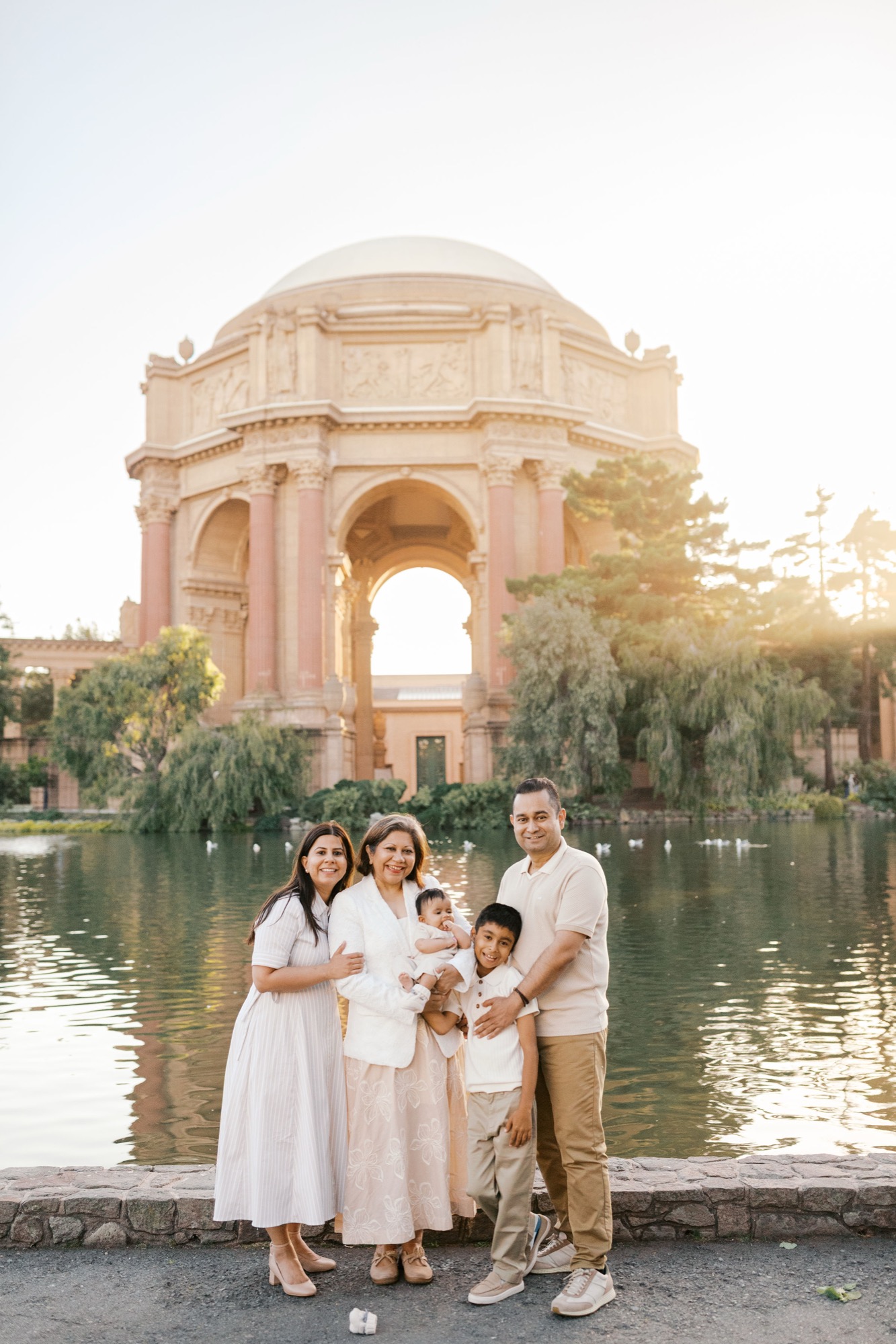 Family of five at the edge of the lagoon with the Palace of Fine Arts rotunda and its reflection behind them