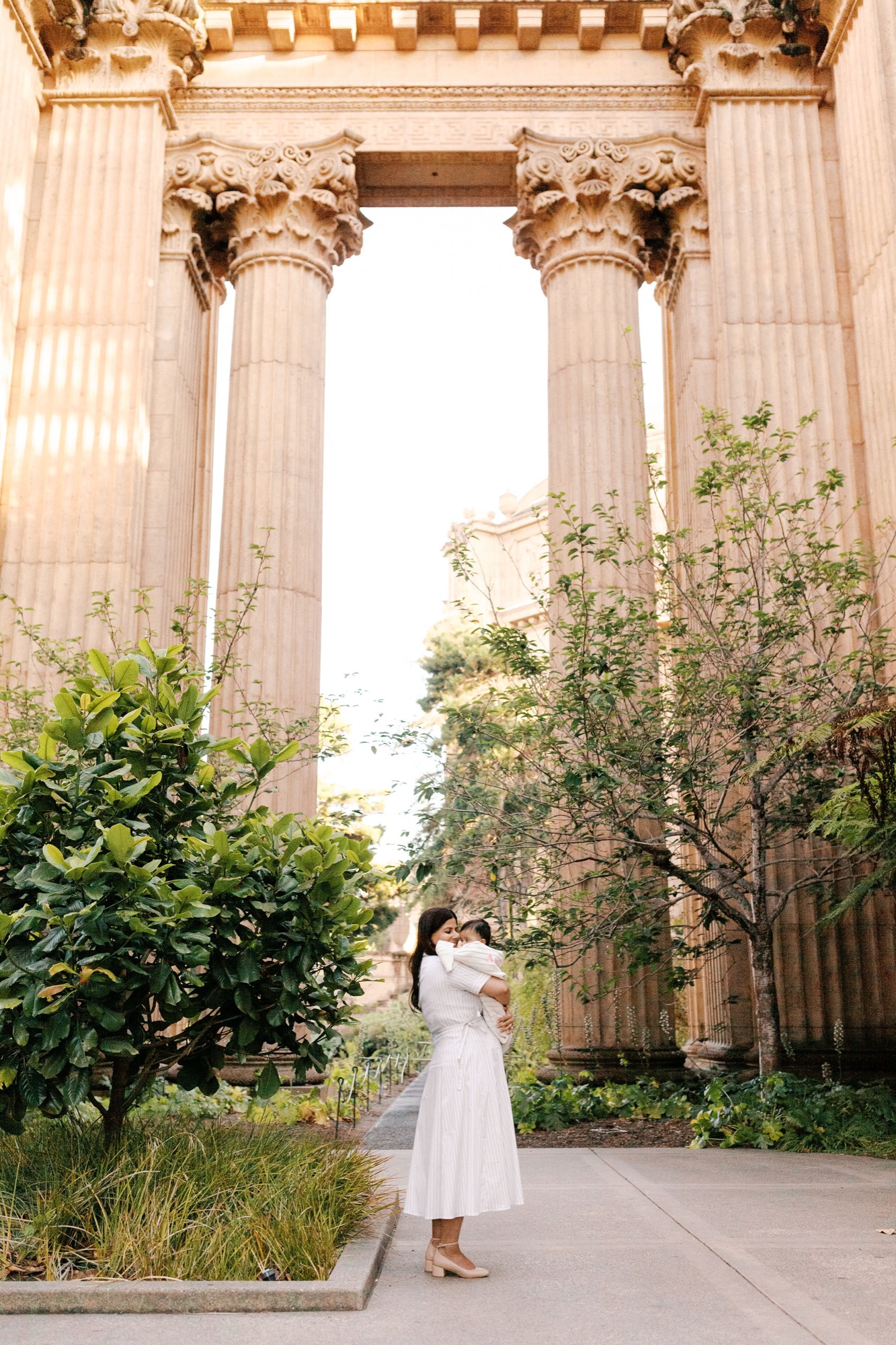 Mom holds her baby beneath the towering Corinthian columns of the Palace of Fine Arts colonnade