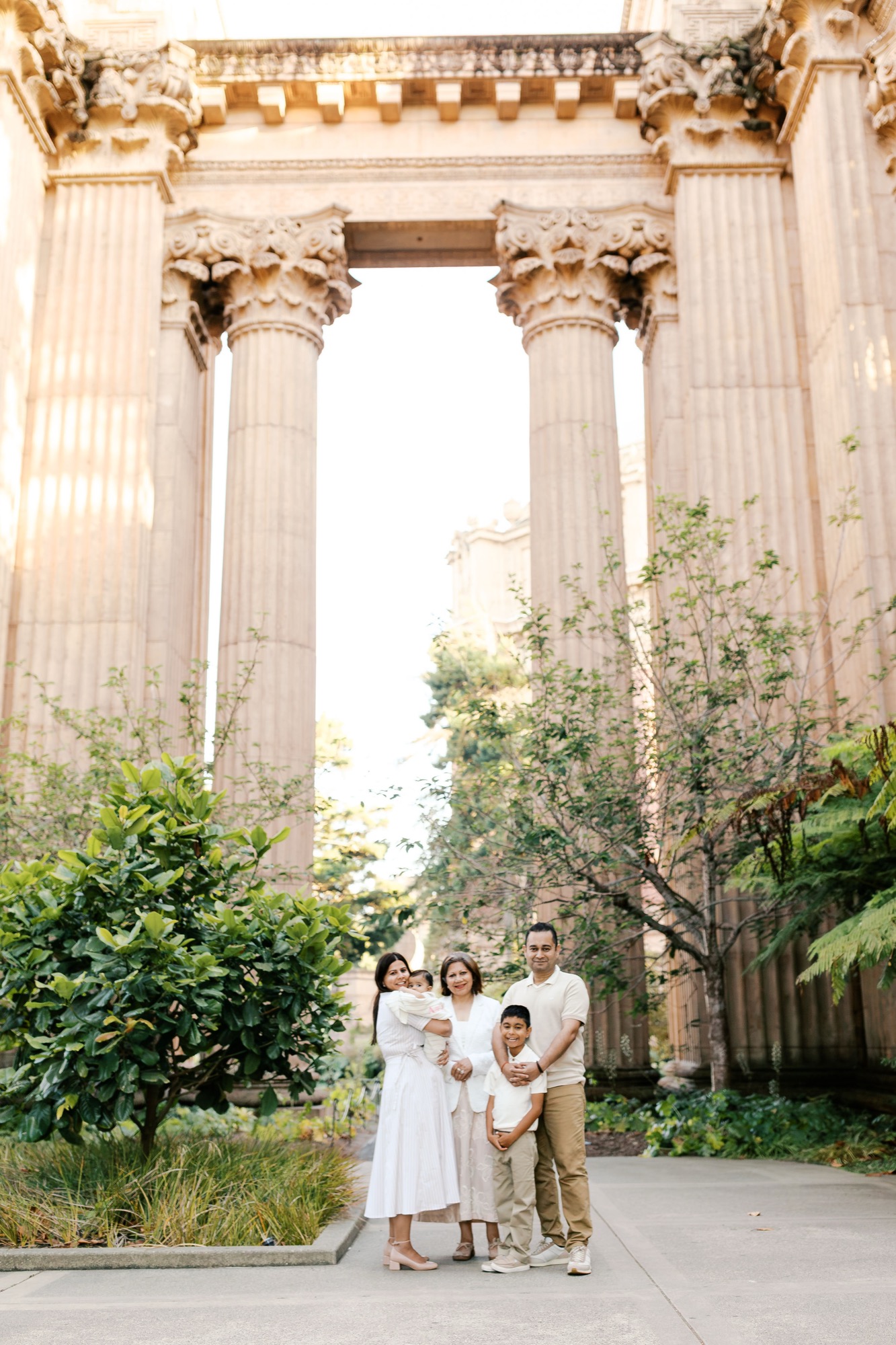 Family of five standing small beneath the towering columns of the Palace of Fine Arts colonnade