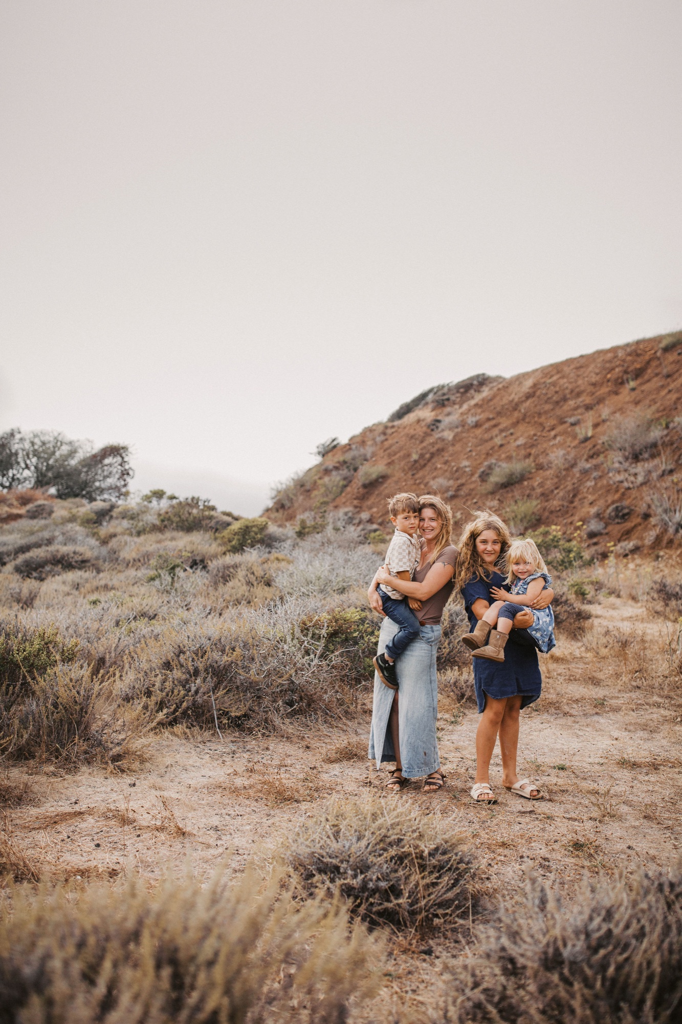 Family standing together on the dirt path through the coastal scrub in Sausalito, headlands rising behind