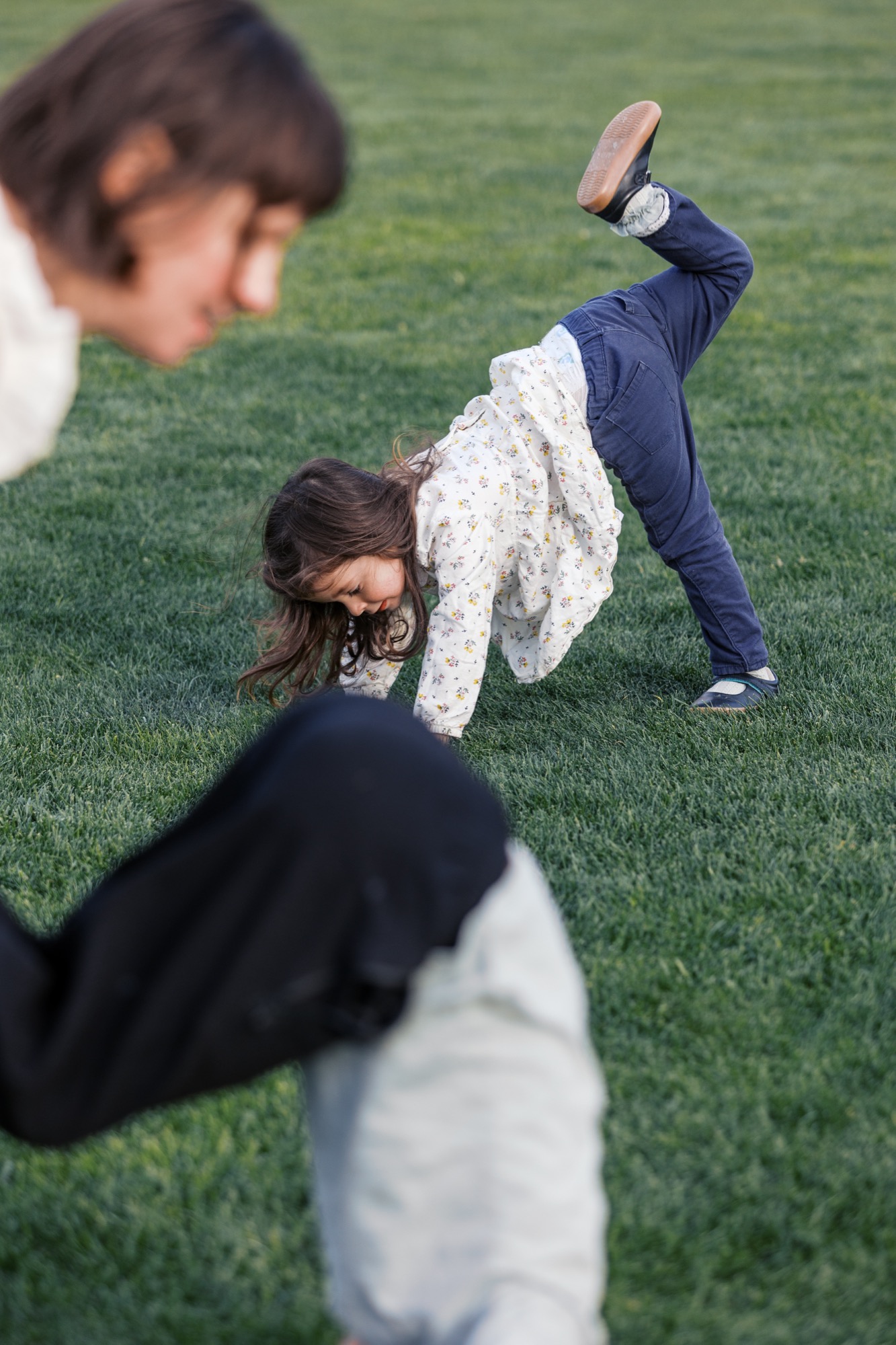 Children tumble and play on manicured grass while one child cartwheels in afternoon sunlight at the Presidio