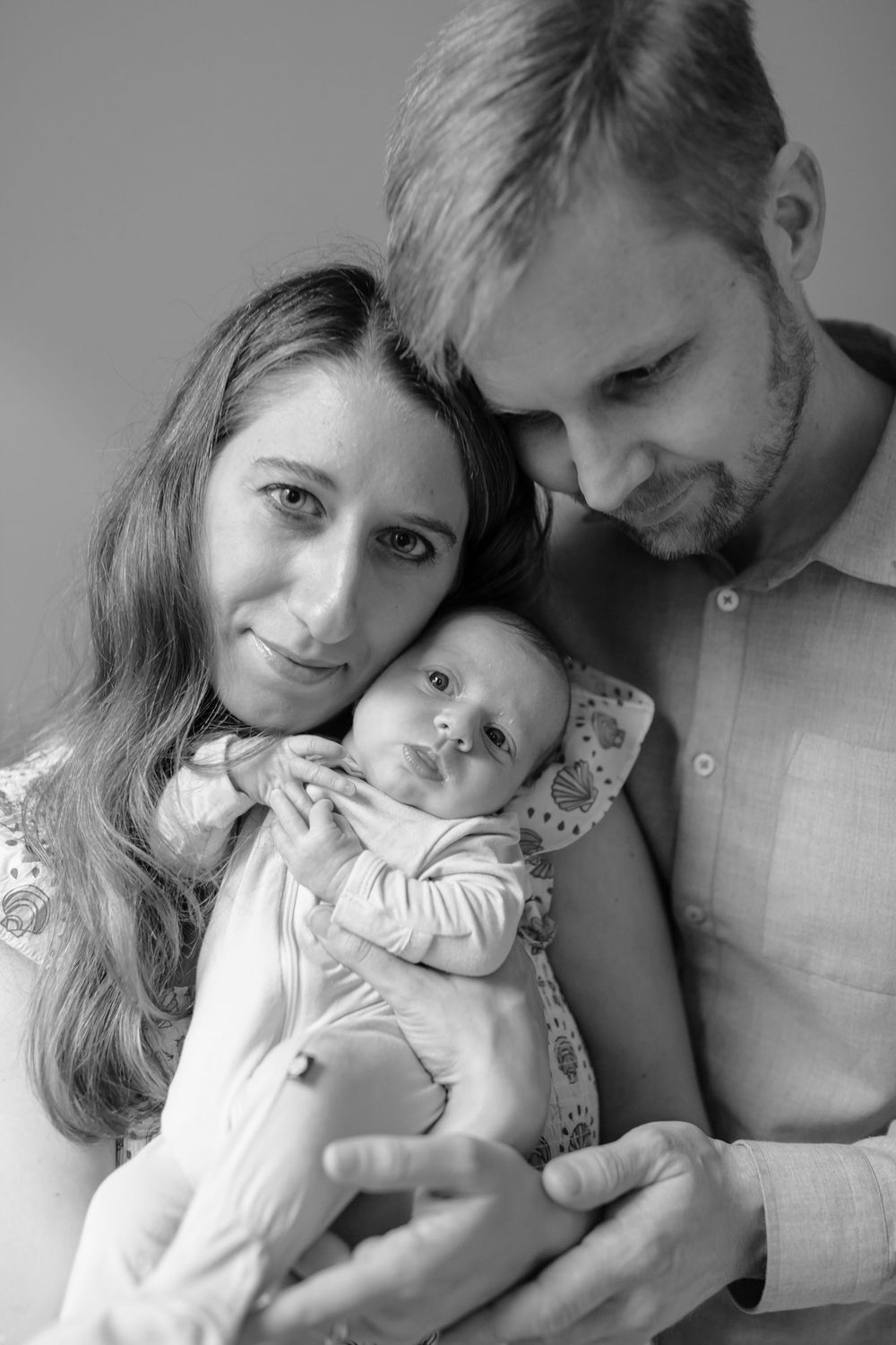 Black and white portrait of parents and newborn baby close together