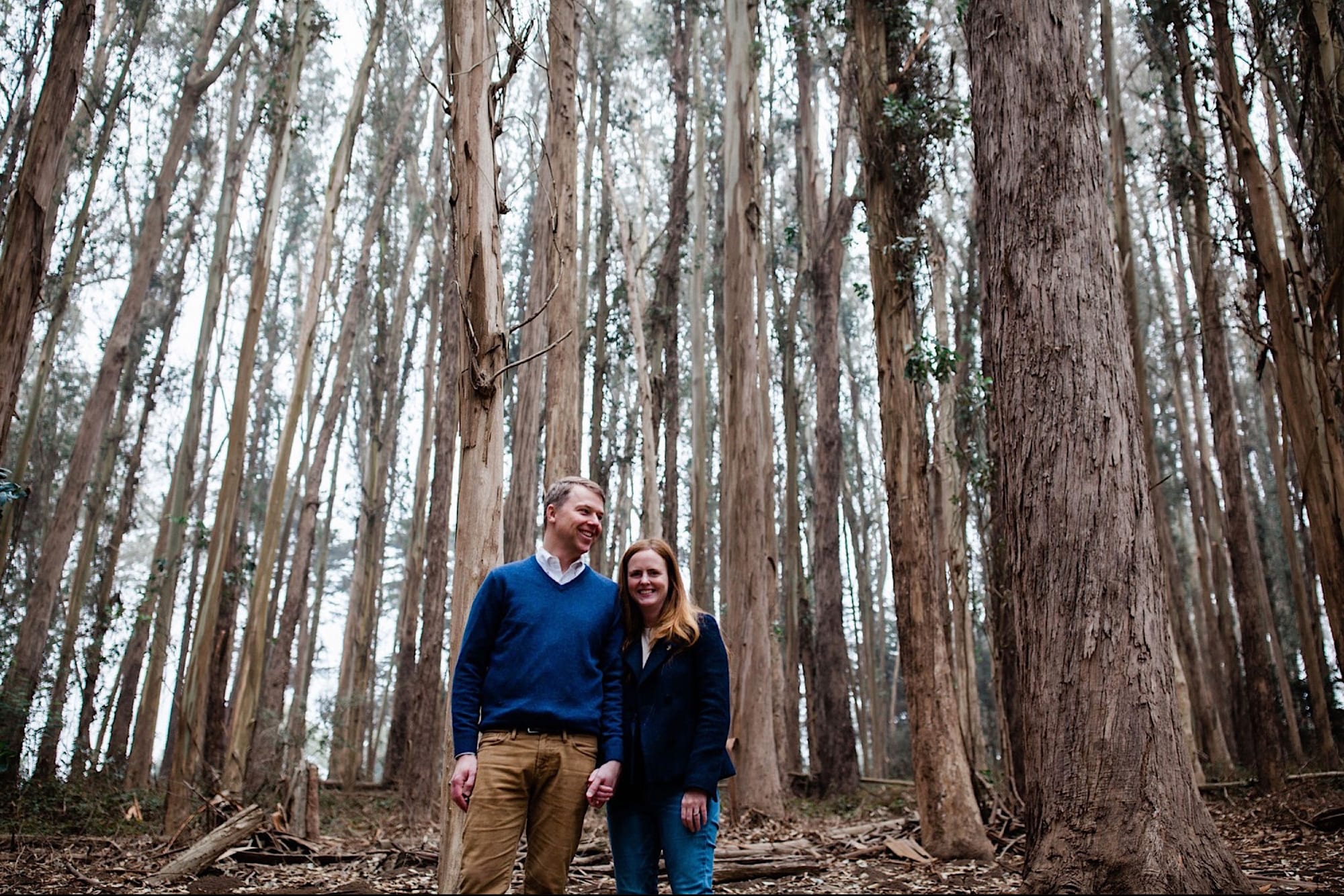 Couple standing hand in hand beneath the towering eucalyptus trunks of Lovers Lane, San Francisco